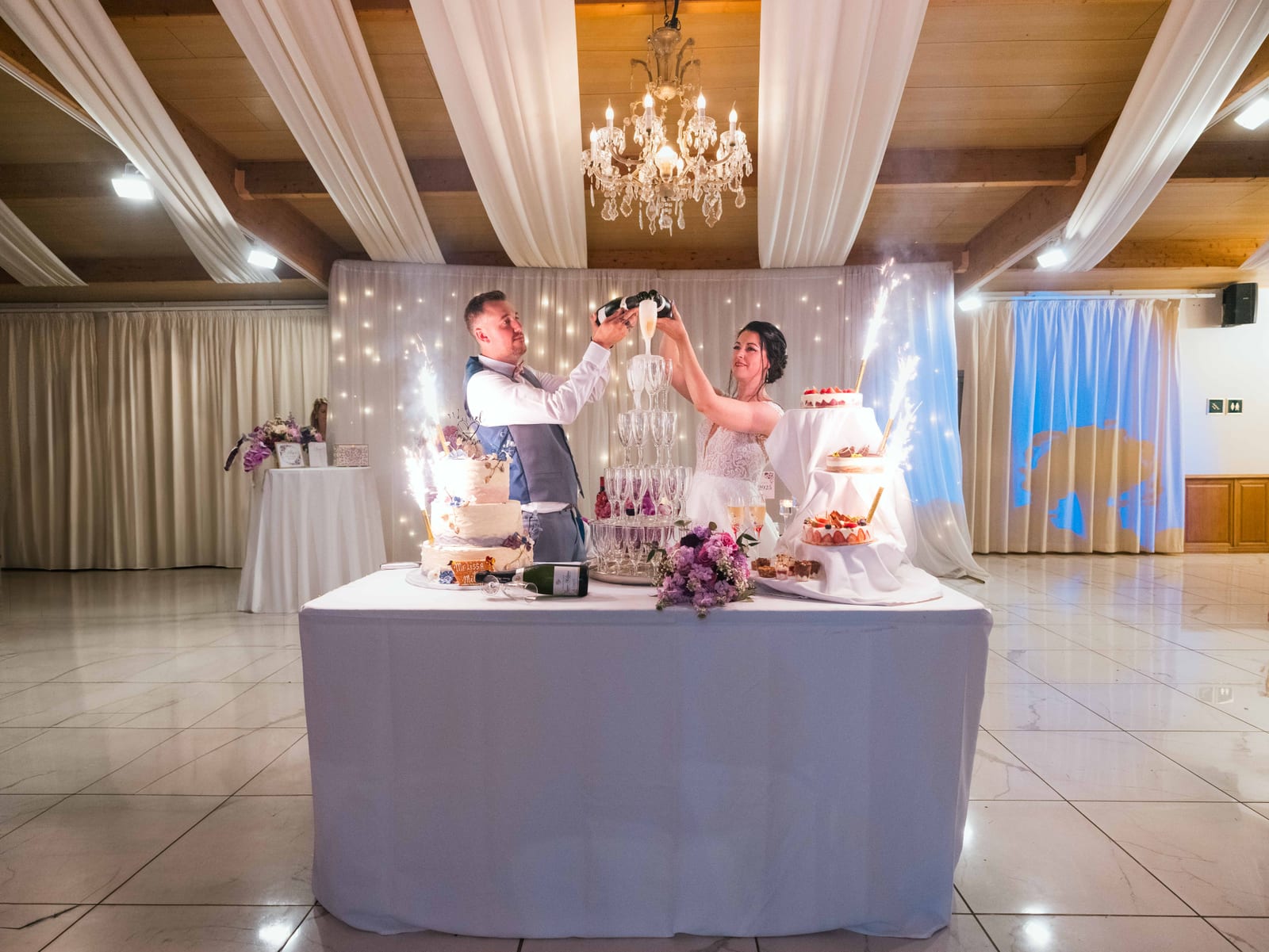 Couple au gâteau de mariage, table couverte d'une nappe blanche dans la salle, mariage au Domaine de la Muette, par Jean-Baptiste Argyre (Jaysphotography)