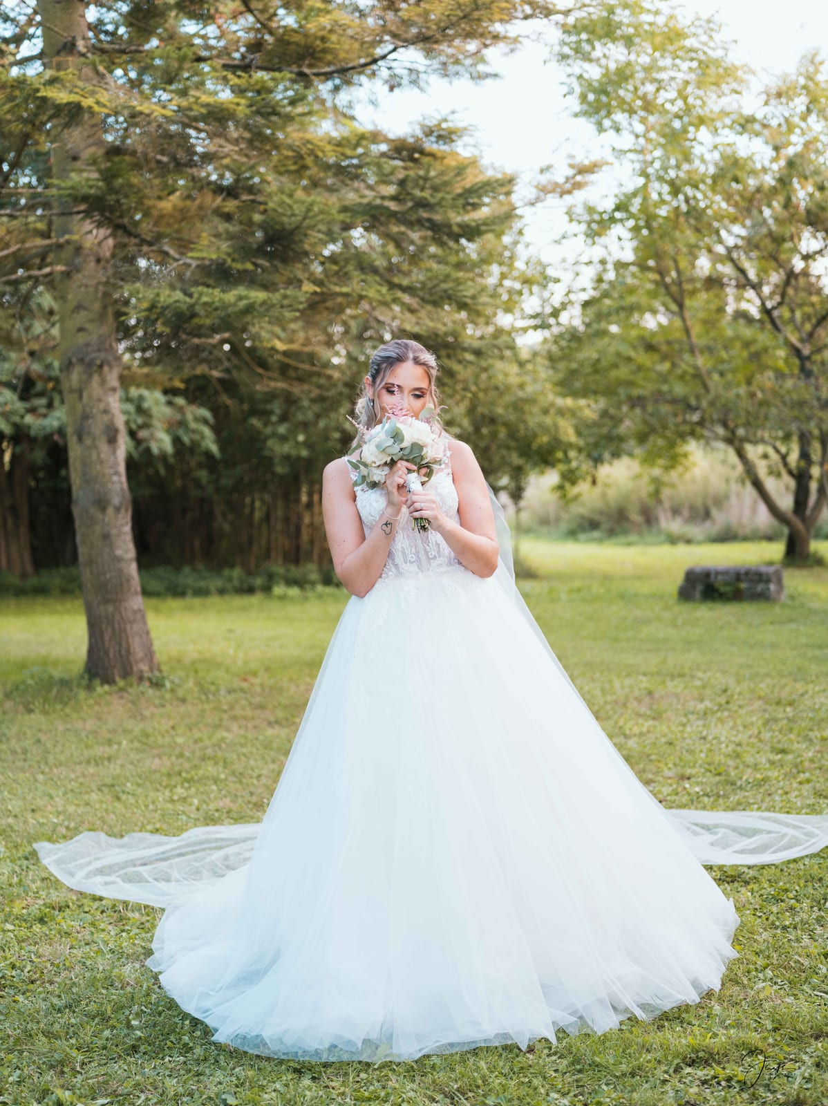 Ophélie seule dans le parc, longue traîne étalée sur l'herbe, pose naturelle et sereine, mariage au Domaine de Monceaux, par Jean-Baptiste Argyre (Jaysphotography)
