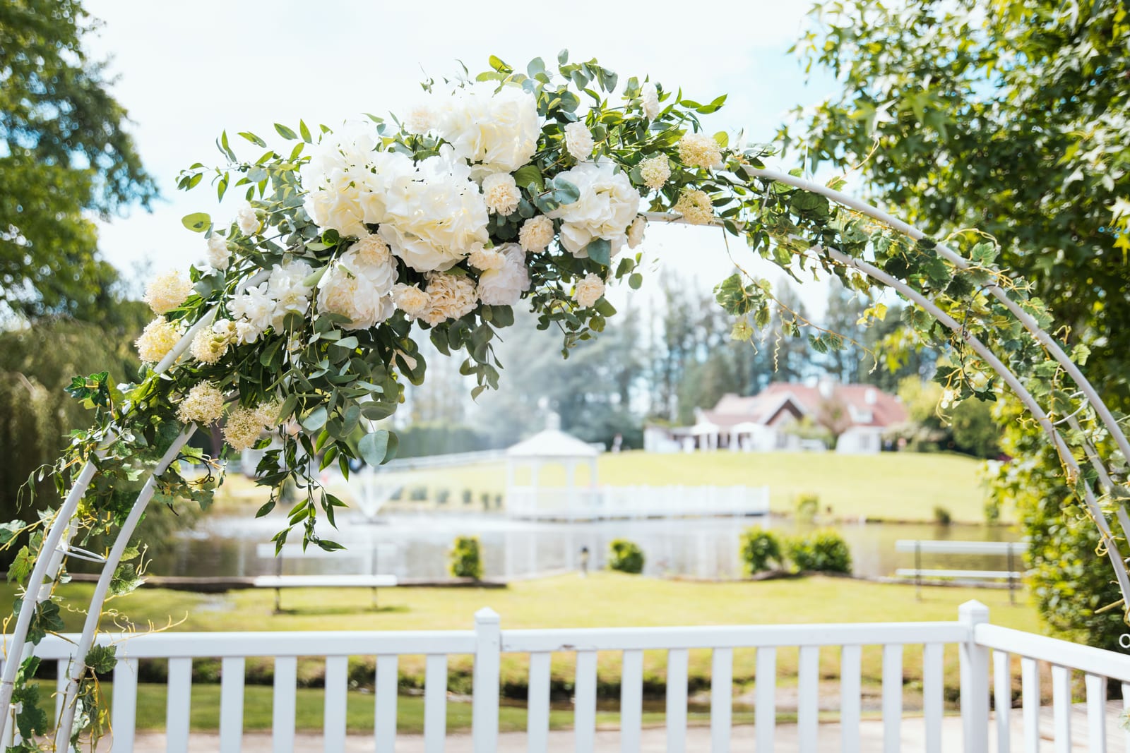 Arche florale blanche pour la cérémonie laïque en extérieur, chaises blanches alignées, mariage au Domaine de Fontanelle, par Jean-Baptiste Argyre (Jaysphotography)
