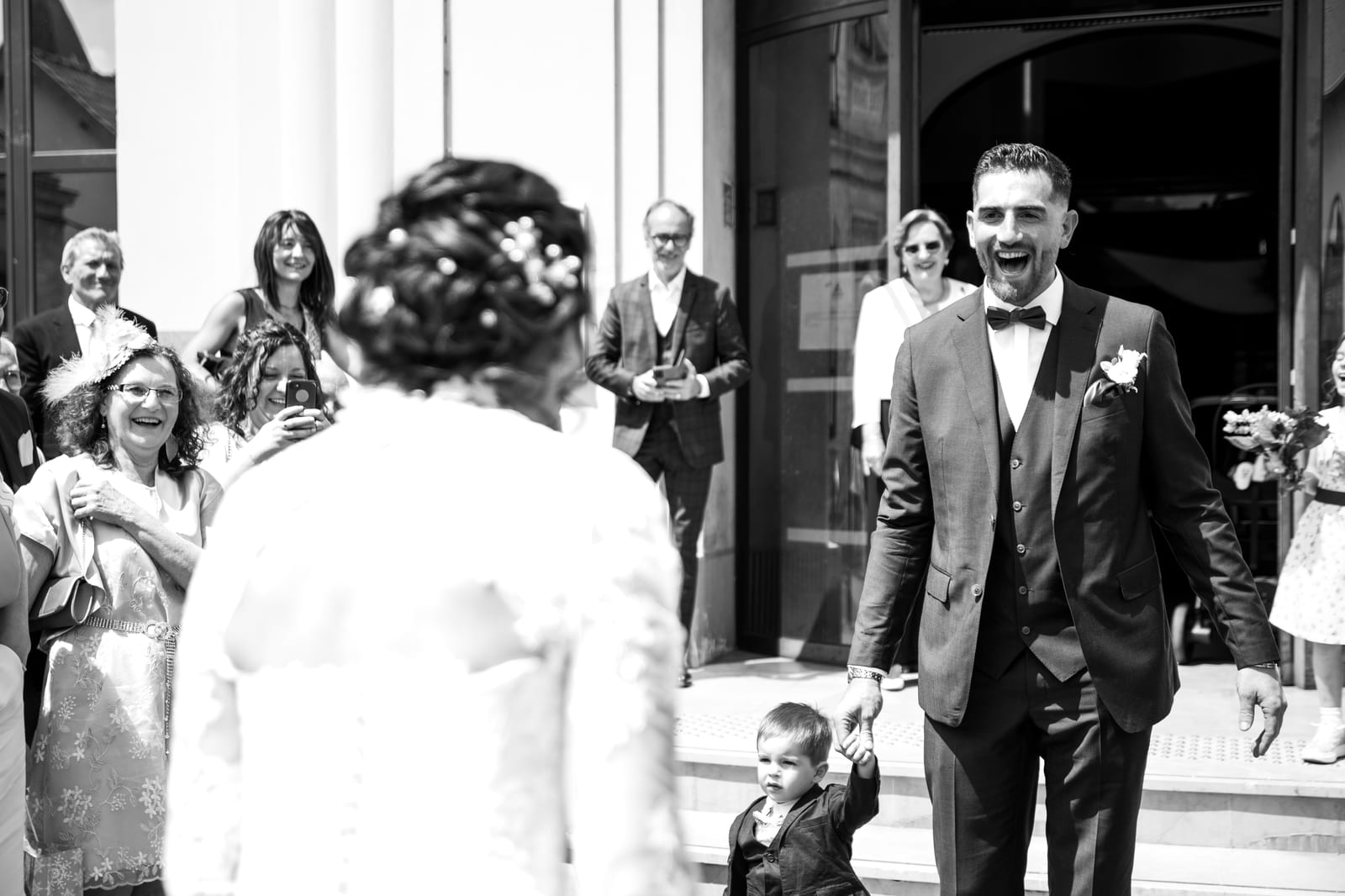 Anthony entre dans la salle de reception en noir et blanc, invités qui applaudissent, mariage au Domaine de Fontanelle, par Jean-Baptiste Argyre (Jaysphotography)