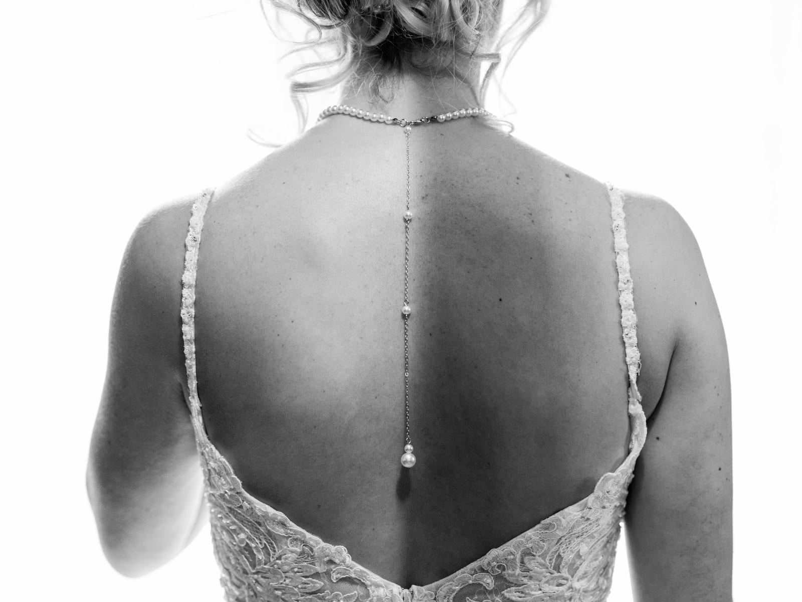 Gros plan sur le dos nu de Julie en robe de mariée, boutons nacrés, préparatifs mariage Domaine des Saules, mariage au Domaine des Saules, par Jean-Baptiste Argyre (Jaysphotography)
