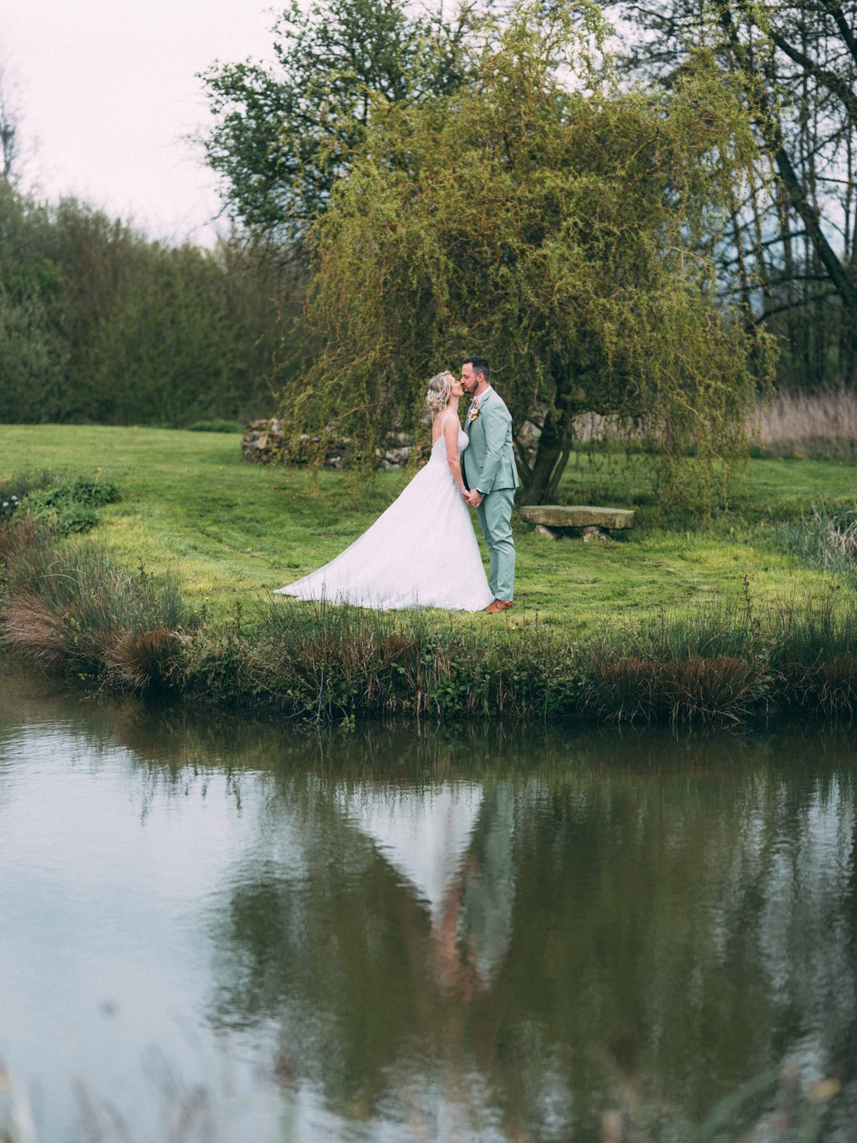 Romain et Julie en couple au bord du lac du Domaine des Saules, végétation printanière verte en fond, Jaysphotography, mariage au Domaine des Saules, par Jean-Baptiste Argyre (Jaysphotography)