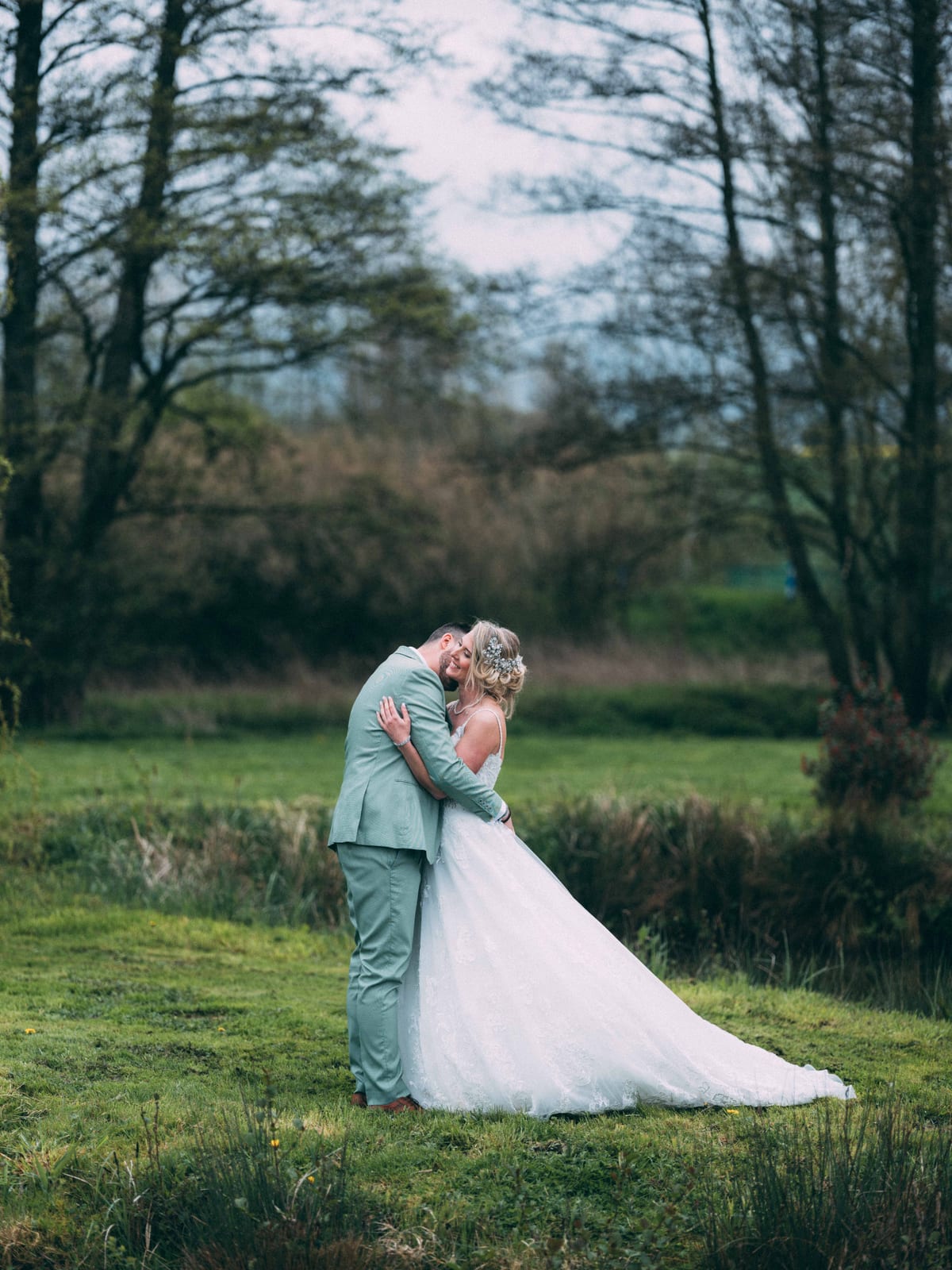Julie en robe de mariée et Romain en costume vert sauge, baiser en extérieur au Domaine des Saules, mariage au Domaine des Saules, par Jean-Baptiste Argyre (Jaysphotography)