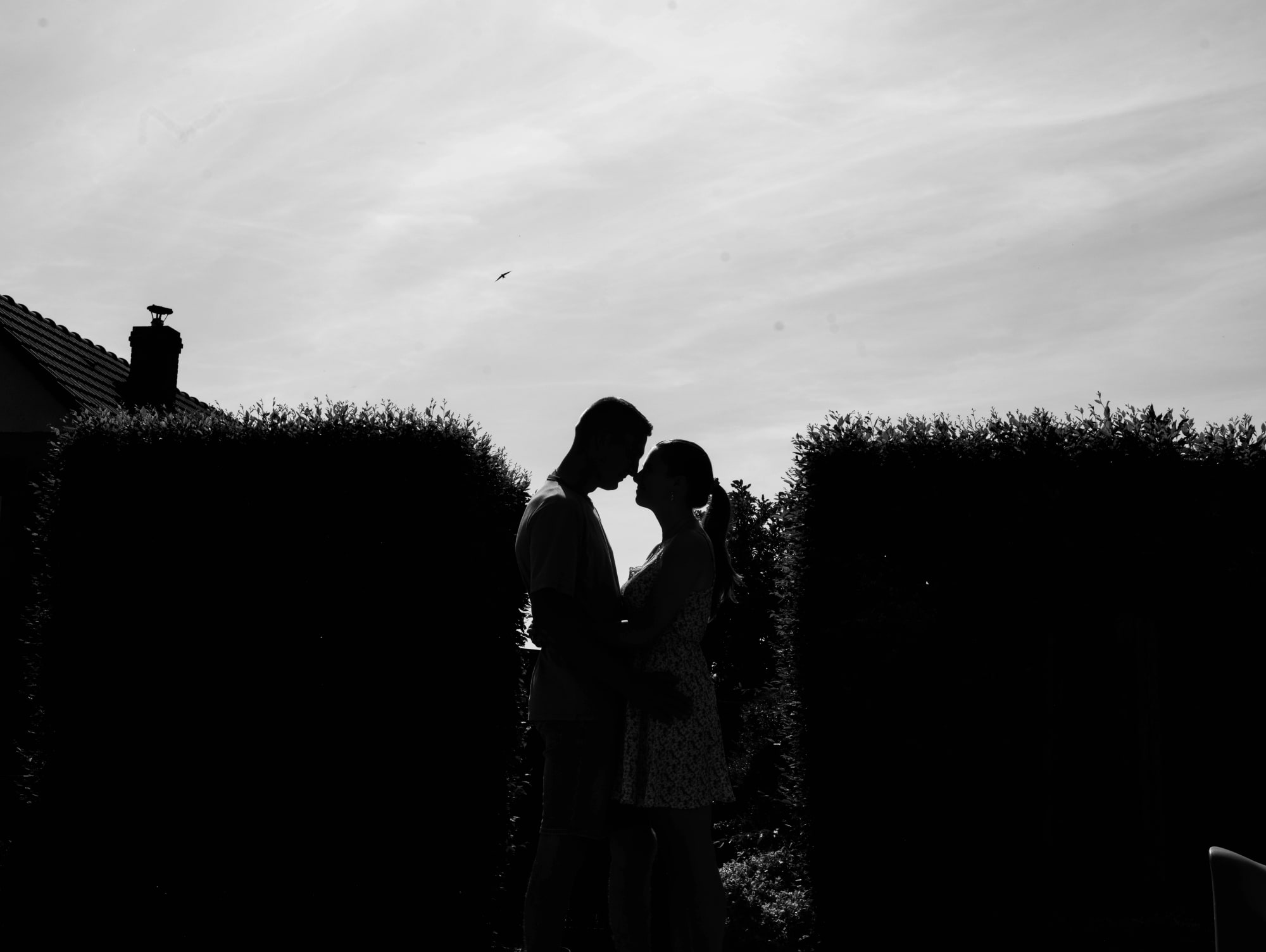 Silhouette du couple en noir et blanc au-dessus des haies du jardin, mariage au Le jardin de la famille, avec piscine (Oise), par Jean-Baptiste Argyre (Jaysphotography)