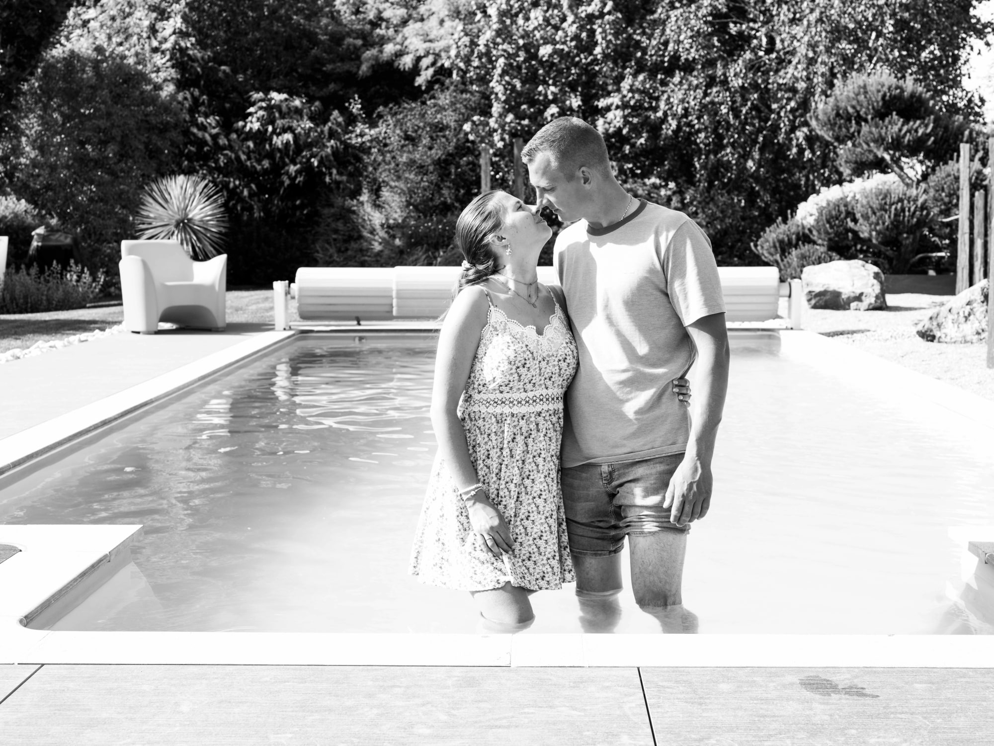 Le couple les pieds dans l'eau au bord de la piscine, en noir et blanc, mariage au Le jardin de la famille, avec piscine (Oise), par Jean-Baptiste Argyre (Jaysphotography)
