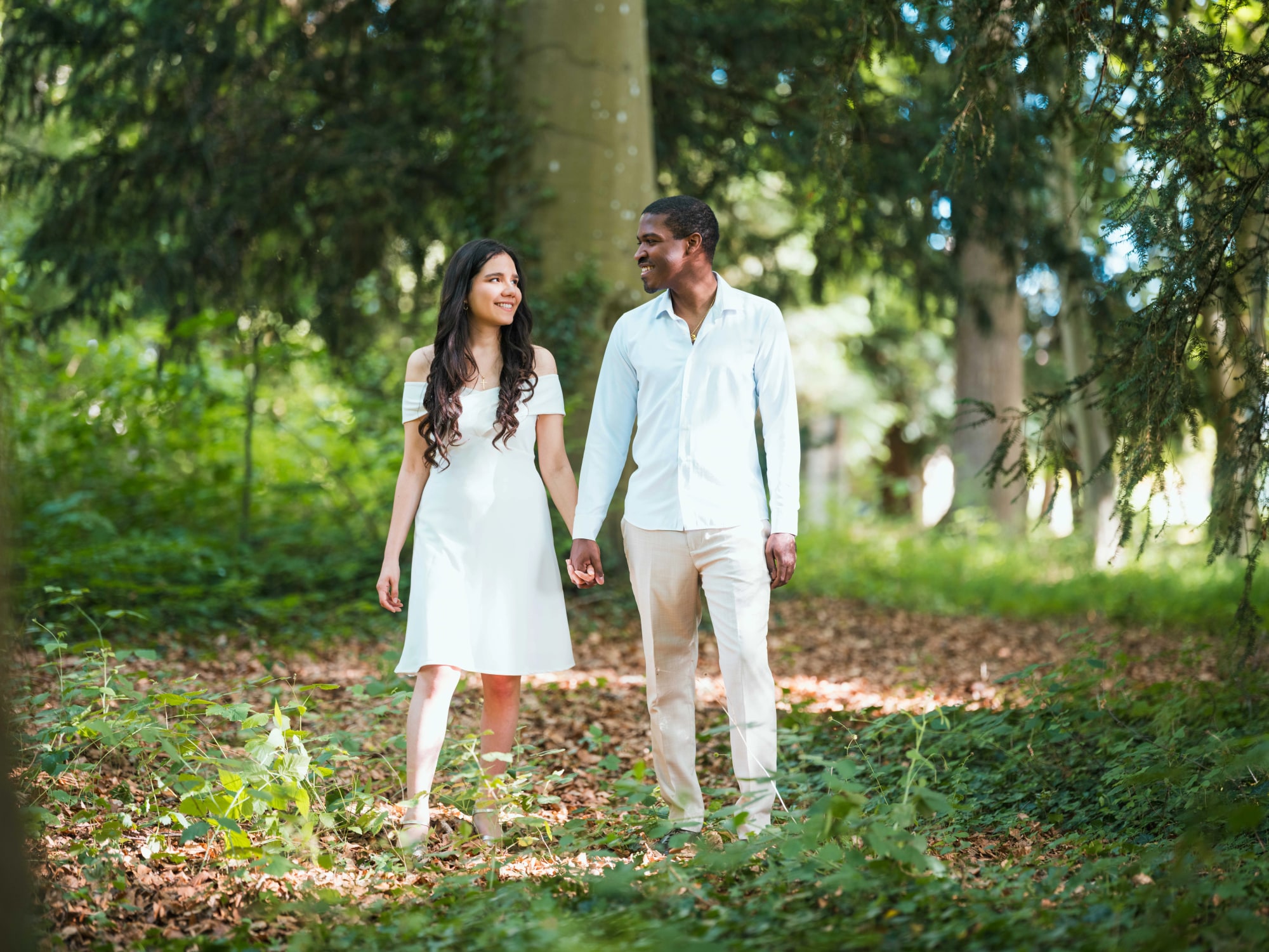 Cindy et Printis main dans la main sur le chemin forestier du parc, mariage au Château de Lamorlaye, par Jean-Baptiste Argyre (Jaysphotography)
