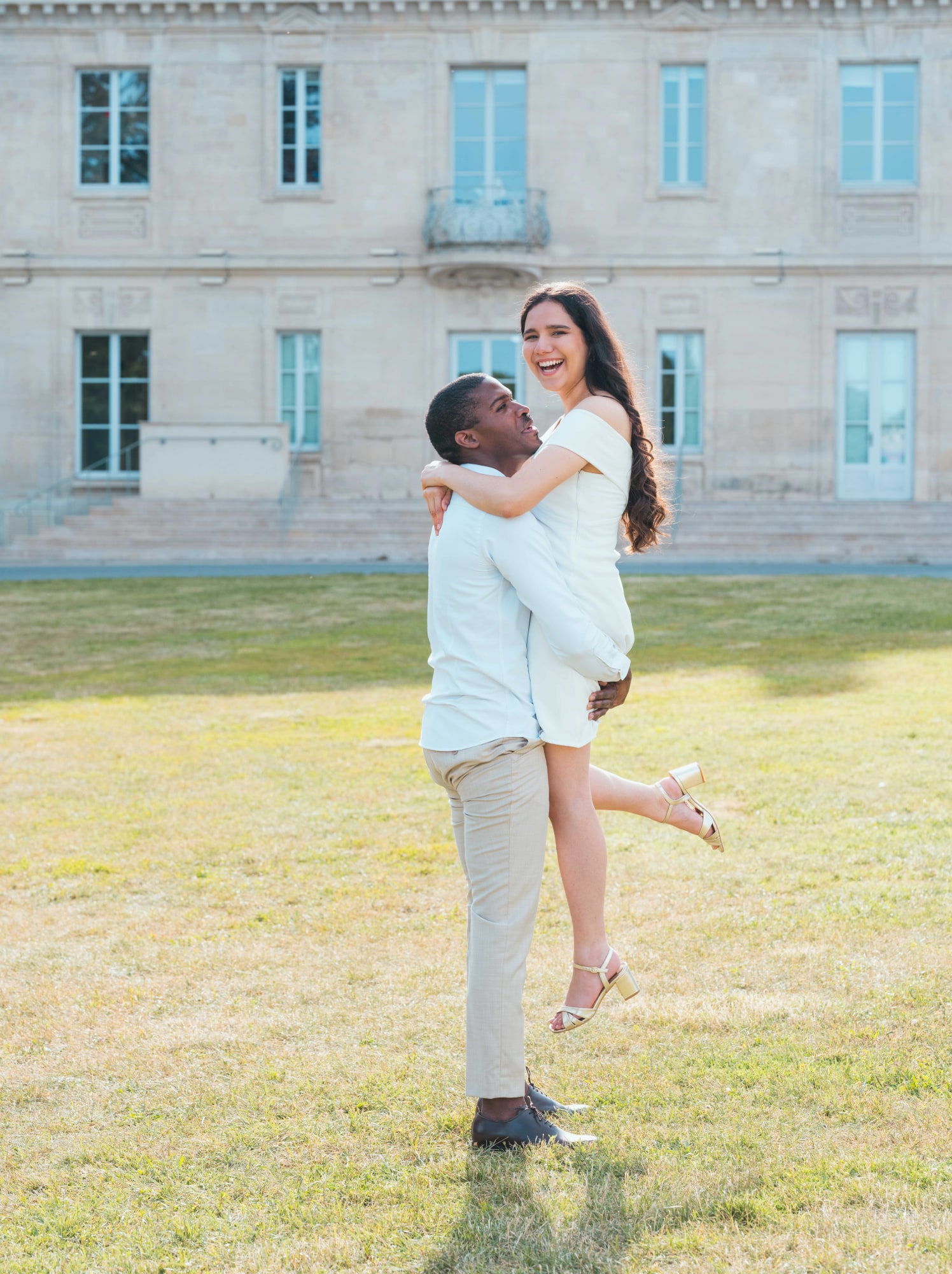Porté de Cindy dans les bras de Printis sur la pelouse du château, mariage au Château de Lamorlaye, par Jean-Baptiste Argyre (Jaysphotography)