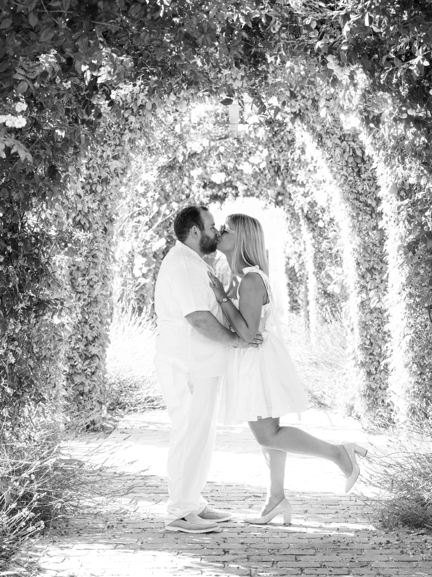 Baiser de Kazia et Lucas sous les arches de la Maladrerie, en noir et blanc, mariage au Maladrerie Saint-Lazare (Beauvais), par Jean-Baptiste Argyre (Jaysphotography)