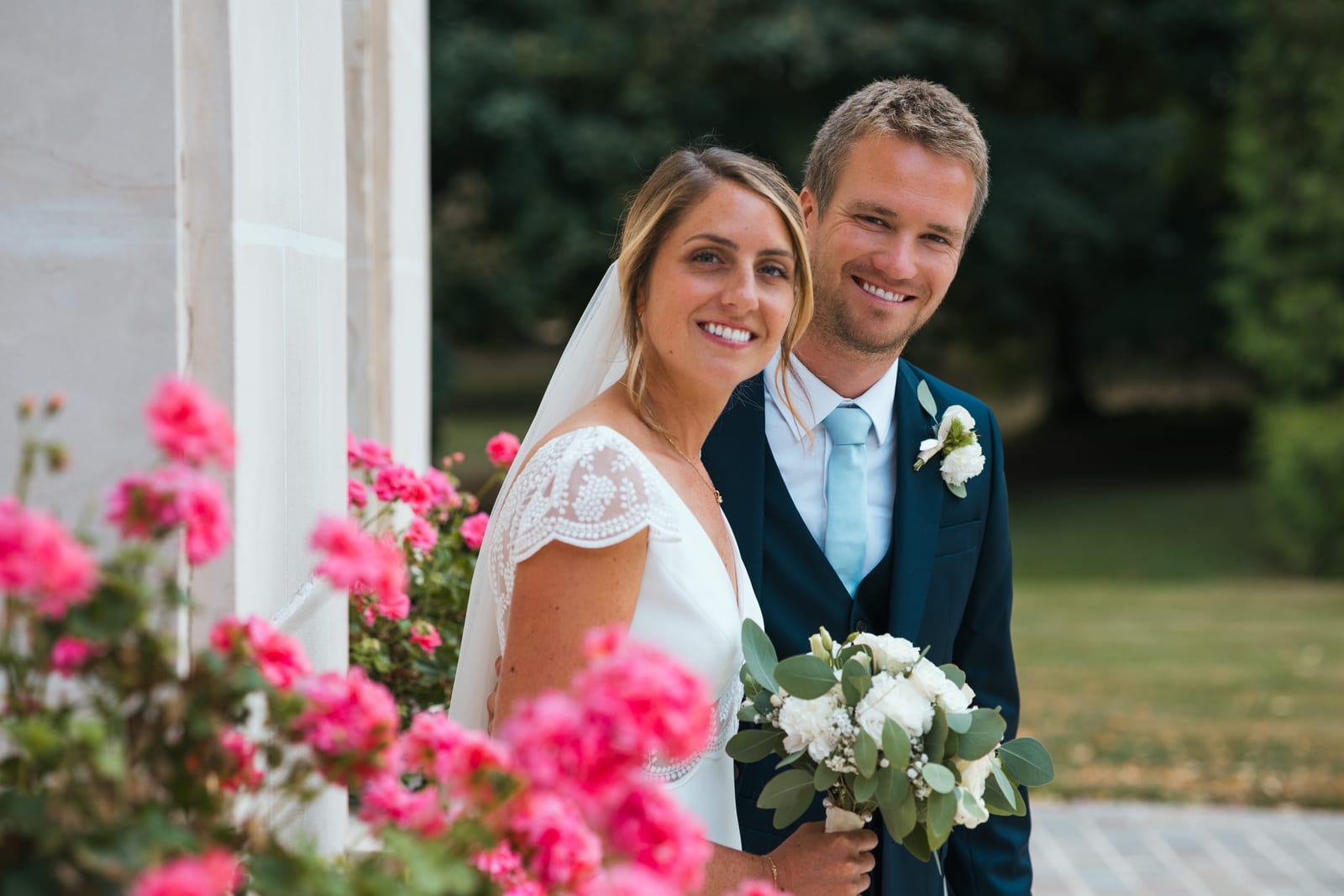 Couple Thomas et Inès en extérieur avec massif de fleurs roses vives en premier plan, Château des Granges (Oise), Jaysphotography., mariage au Château des Granges, par Jean-Baptiste Argyre (Jaysphotography)