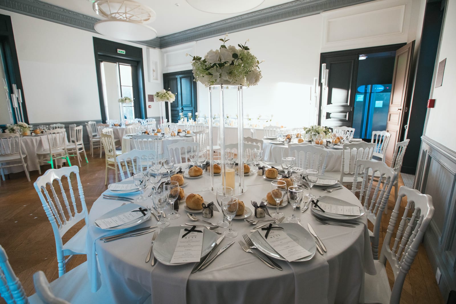 Décoration de la salle de réception du Château de Lamorlaye, tables dressées en blanc avec bougies et verres à tige, ambiance élégante, mariage au Château de Lamorlaye, par Jean-Baptiste Argyre (Jaysphotography)