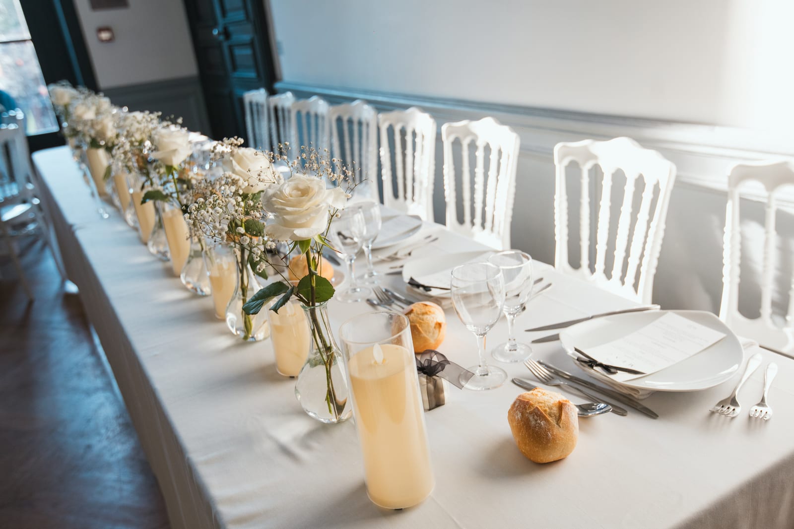 Vue panoramique de la salle de réception en longueur, nappes blanches, guirlandes lumineuses au plafond, mise en place avant le repas, mariage au Château de Lamorlaye, par Jean-Baptiste Argyre (Jaysphotography)