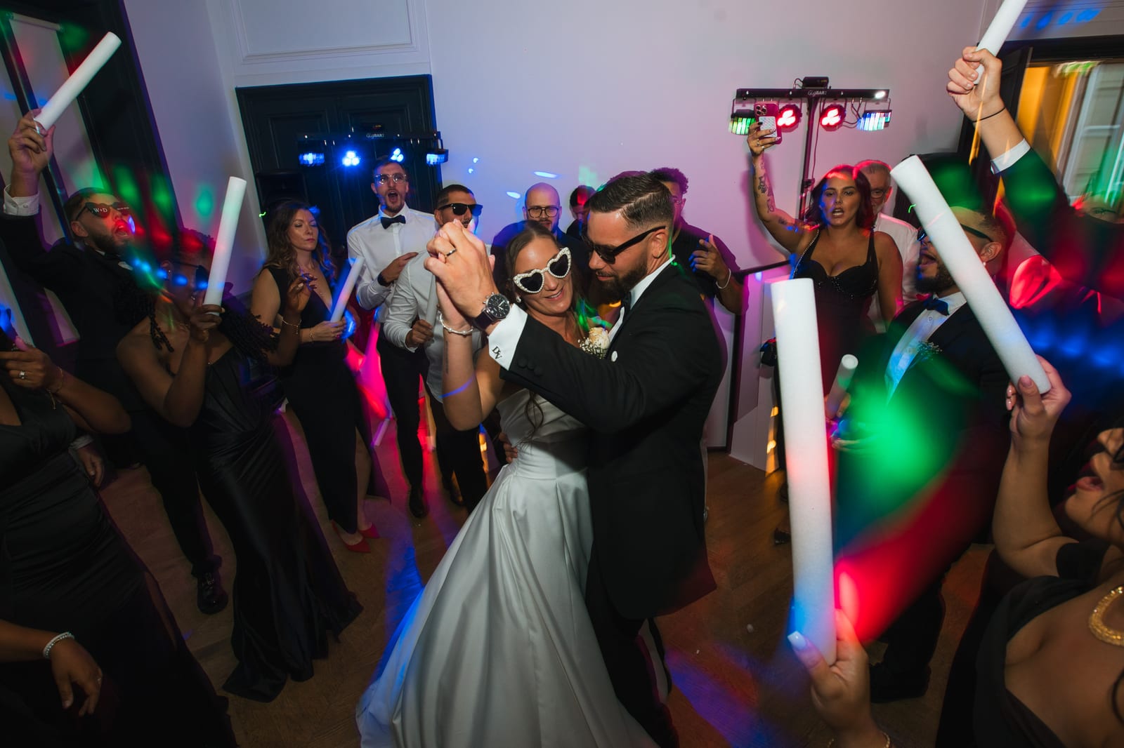 Wendy et Daniel en pleine danse d'ouverture de bal, robe blanche contrastant avec l'ambiance sombre et festive de la salle, mariage au Château de Lamorlaye, par Jean-Baptiste Argyre (Jaysphotography)