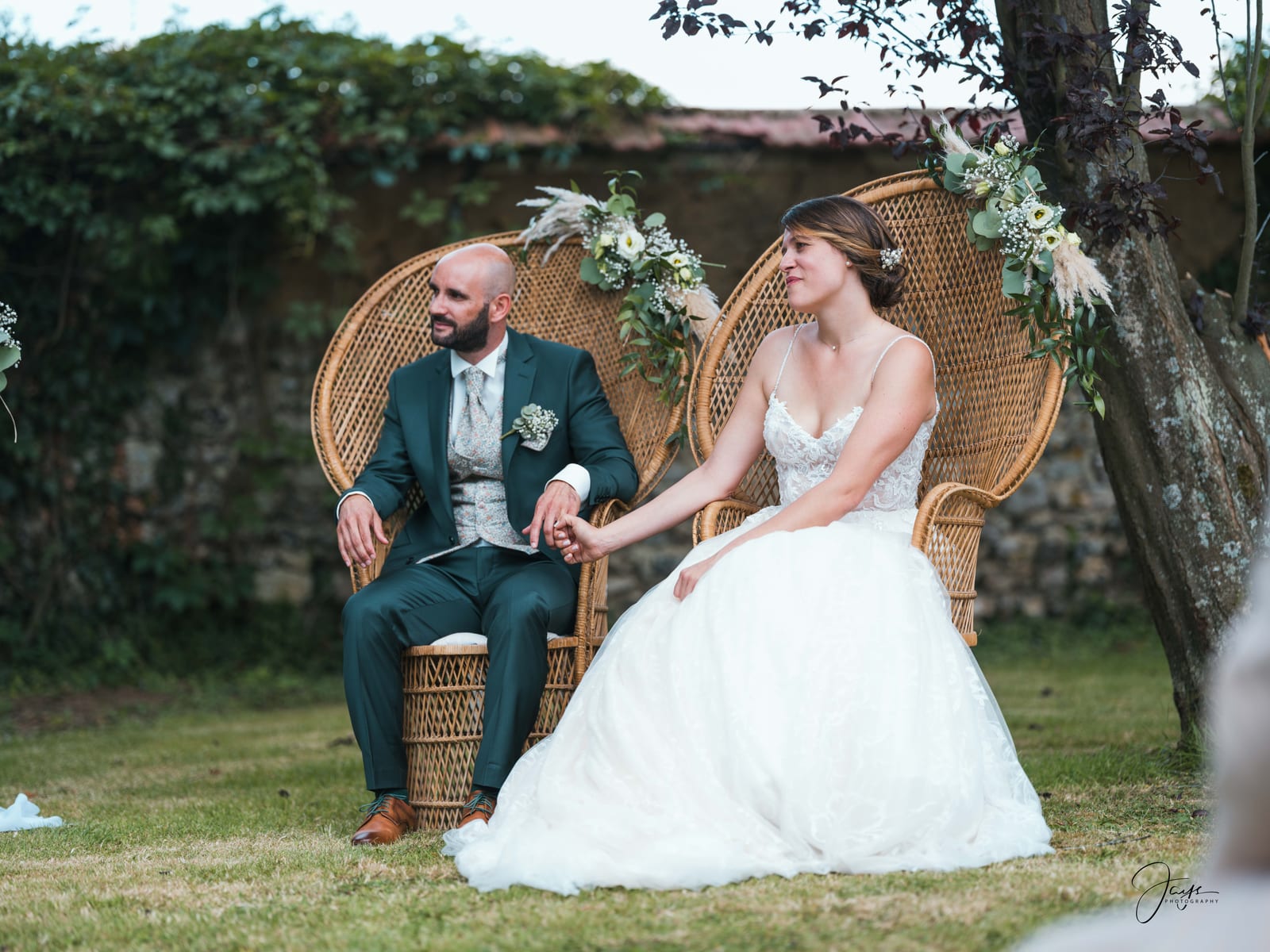 Yohan et Julie assis dans un fauteuil en rotin lors de la cérémonie au Domaine de la Croix Sauvalle, mariage au Domaine de la Croix Sauvalle, par Jean-Baptiste Argyre (Jaysphotography)